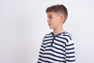 Side view of young happy smiling little cute boy kid wearing stripped t-shirt against white wall © Jihan