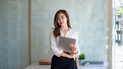 Image of an asian businesswoman with confidence and creativity. Using a tablet at the office. - Powered by Adobe