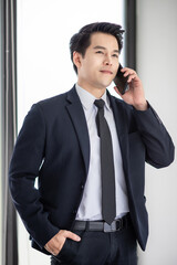 Young asian businessman wear modern suit. Talk on the mobile phone at the office.