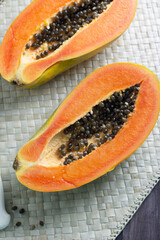 Pepaya or ripe papaya fruit one of tropical fruit in Indonesia. Cut into pieces on woven matt background. Close up view, copy space for text.