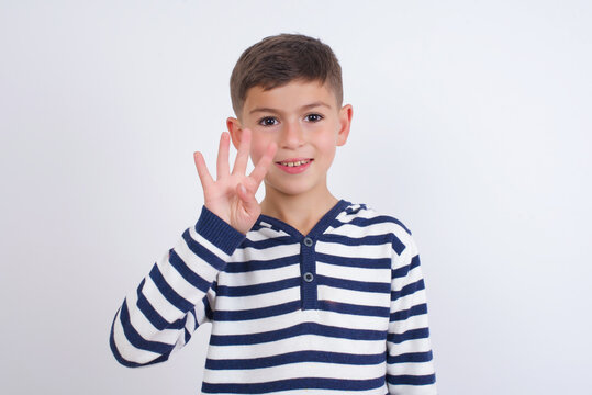 little cute boy kid wearing red stripped t-shirt against white wall showing and pointing up with fingers number four while smiling confident and happy.