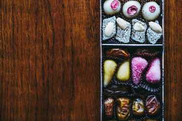 Boîte de friandises avec des chocolats pâtes de fruits et fruits secs posée sur un fond en bois...