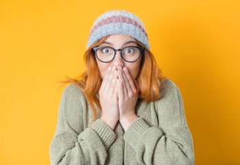 Astonished woman covers her mouth, isolated on yellow background. Surprised girl. Unbelievable concept