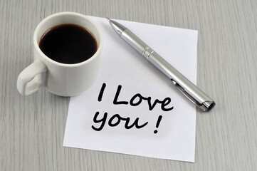 Je t'aime écrit en anglais sur un morceau de papier à côté d'une tasse de café