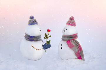 Snowmen in love wearing winter hats, scarves on a white background in pink and blue colors. Boy giving a rose flower to girl. Valentins day, love concept. 14th february.
