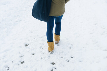 Shopping bag walk. Girl walking on snow. Winter walk background. Female student walking in park. Jeans trousers and warm shoes.