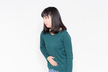 白背景の前に立って、お腹に手を当てている女性