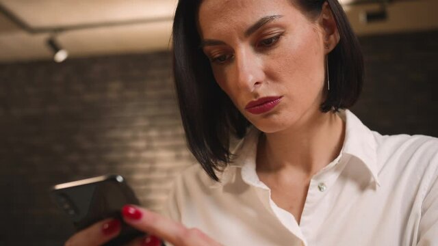 Closeup. Pretty caucasian businesswoman uses the phone, reads the news, browses social networks, communicates with colleagues.