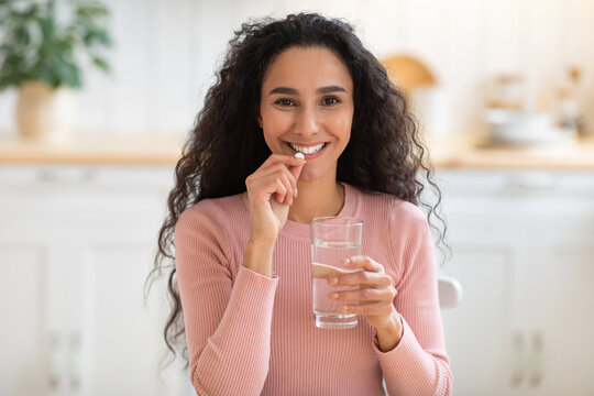 Beauty Supplement. Smiling Brunette Woman Taking Vitamin Pill And Drinking Water