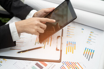 Asian accountant working and analyzing financial reports project accounting with chart graph and...