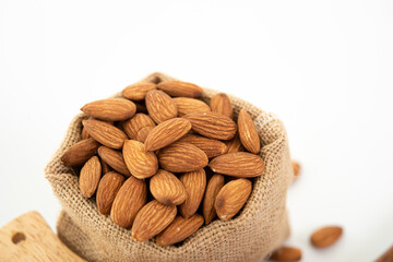 Sack with almond on white background. (selective focus; close-up shot)