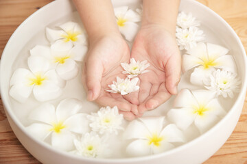 Plakat Spa treatment and product for female feet and hand spa. white flowers in ceramic bowl with water for aroma therapy at spa.