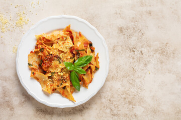 Pasta Maltagliati with classic tomato sauce, parmesan and basil on a rustic concrete light table background. Traditional Italian dish serving. Top view.