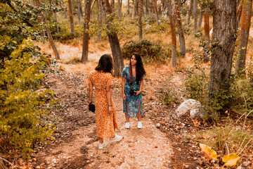Fototapeta premium Two young lesbians walking in the woods wearing long dresses