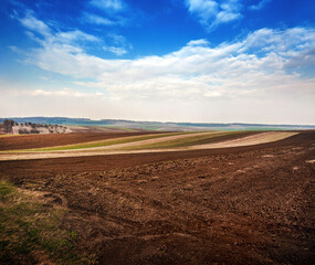 Fototapeta na wymiar spring field, plowed soil and hills landscape in the background