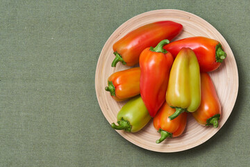 The colored pepper lies on a slide on a wooden plate on a green napkin with text area. The view from the top.