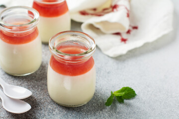 Festive dessert with berry jelly, vanilla panna cota and fresh strawberry on gray concrete table background. Selective focus.
