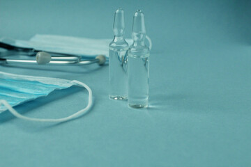 Vaccination medicine mask syringe medicine vitamins in glass vials on a blue blue background with a...