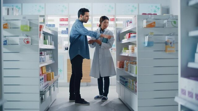 Pharmacy Drugstore: Female Asian Pharmacist Helping Latin Male Customer with Recommendation, and Advice to Buy Medicine, Drugs, Vitamins. Modern Pharma Store Shelves with Health Care Products
