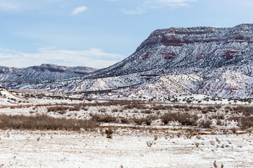 Corner of snow covered mountain range with large open field on bright day in rural New Mexico