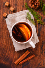 Cup of hot tea with orange and spices on a rustic brown background. Close-up