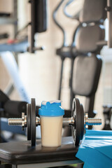 Protein sports shake, elastic tape and dumbbells in the home gym.
