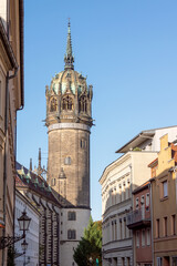 Fototapeta na wymiar Häuserzeile und Turm der Schlosskirche in der Schlossstraße in der Lutherstadt Wittenberg, Sachsen-Anhalt
