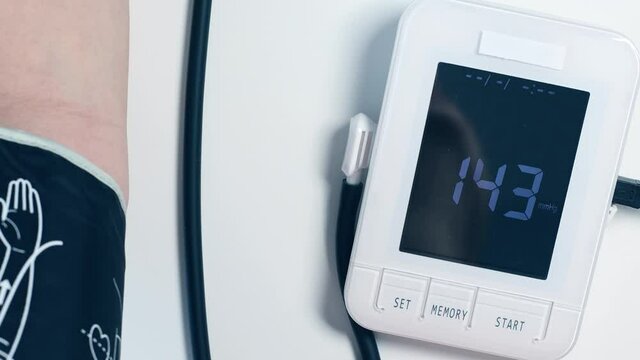 Adult or old woman measures blood pressure with portable digital tonometer at home.