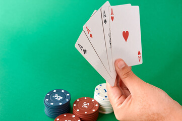 Stack of chips and hand with four aces, Poker cloth, a deck of cards, poker hand and chips. Background.