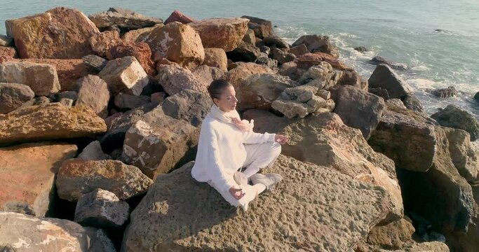 vuelo dron sobre mujer sentada loto meditando frente al mar