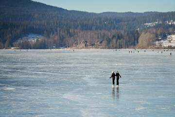 Walking for just the walk is a favorite activity in Norway. Families are gathering at the frozen lake for skating and having fun. It is a cold Sunday in January .