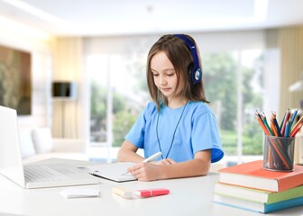 Little girl learning for school desk with headphones