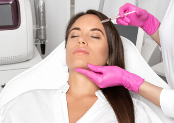 Cosmetologist makes rejuvenating anti wrinkle injections on the face of a beautiful woman. Female...