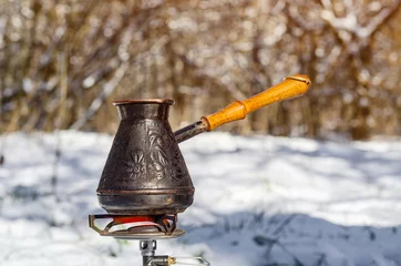 Printed kitchen splashbacks Dhaulagiri Copper Turk with a wooden handle for making coffee on a background of snow in the woods