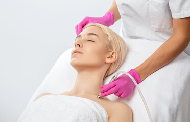 Cosmetologist makes  procedure microdermabrasion on the face against acne and blackheads near the eyes. Women's cosmetology in the beauty salon.