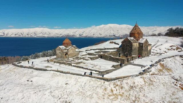 Monastery on snowy mountains background, in  winter time, aerial shot.   Armenian Apostolic Church Hayravank, Gegharkunik Province one of is oldest monastery in Armenia. Near the lake of Sevan.  