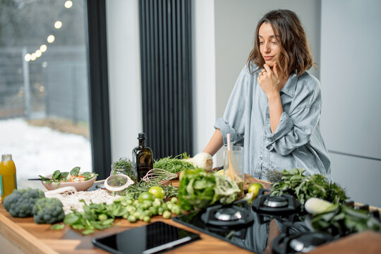 Pretty Woman With Green Ingredients Thinking About Cooking Healthy Food On The Kitchen. Healthy And Wellness Concept. High Quality Photo