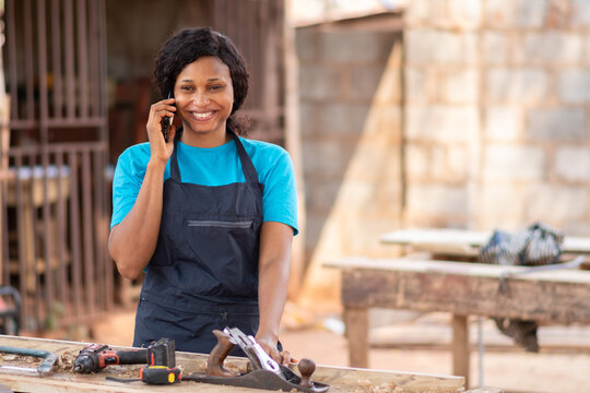 female african carpenter smiling while making a phone call