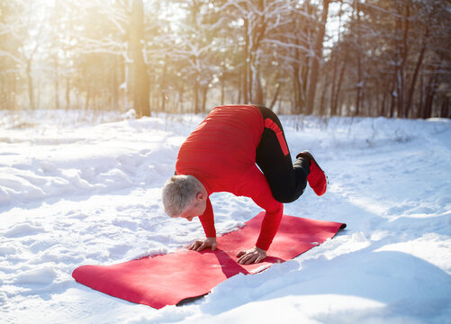 Fit Senior Man Having Outdoor Yoga Practice In Winter At Snowy Forest