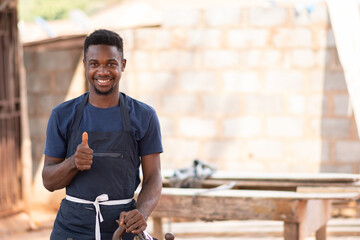 portrait of an african carpenter smiling and giving a thumbs up