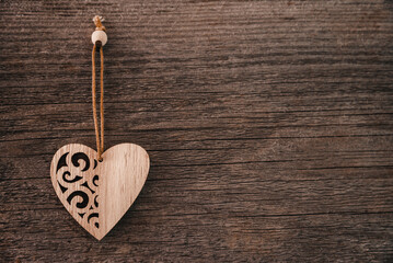Valentine's Day background. Brown natural boards in grunge style with one wooden decorative hearts. Top view. Surface of table to shoot flat lay. Concept love, romantic relation. Copy space for text.