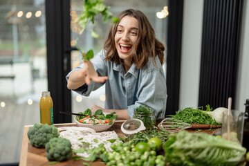 Young pretty woman enjoying and cooking healthy diet salad in the kitchen. Wellness and health care...