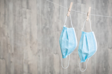 Zwei OP-Masken an der W&auml;scheleine vor einem Holzhintergrund