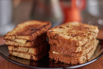 Grilled cheese sandwich on paper on wooden board.