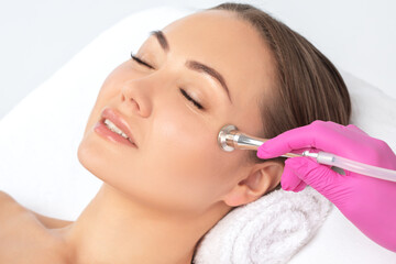 Cosmetologist makes  procedure microdermabrasion on the face against acne and blackheads near the eyes. Women's cosmetology in the beauty salon.