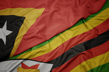 waving colorful flag of zimbabwe and national flag of east timor.
