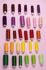 Collection of colored thread layout on a pink background. Handmade and sewing minimal concept. Vertical wallpaper.