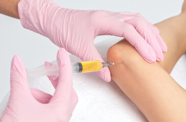 Doctor doing stem cell therapy on a patient's elbow after the injury. Treating knee pain with...