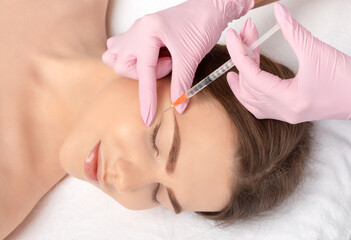 Cosmetologist makes rejuvenating anti wrinkle injections on the face of a beautiful woman. Female...