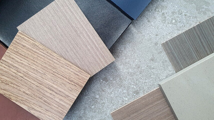 interior material board containing wooden veneer in ash and douglas fir texture samples,grey grained artificial stone or quartz sample ,leather catalog book placed on grey stone concrete tile.
